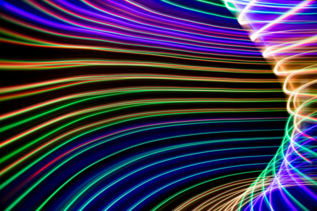 Abstract image of vibrant, colorful light trails forming dynamic shapes on a dark background.